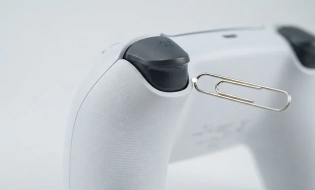 Close-up of PS5 DualSense controller back showing reset button pinhole near L2 button for hard reset