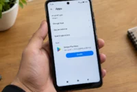 how-to-reinstall-google-play-store-android-settings Hand holding Android phone showing Google Play Store in Settings app with Enable button visible